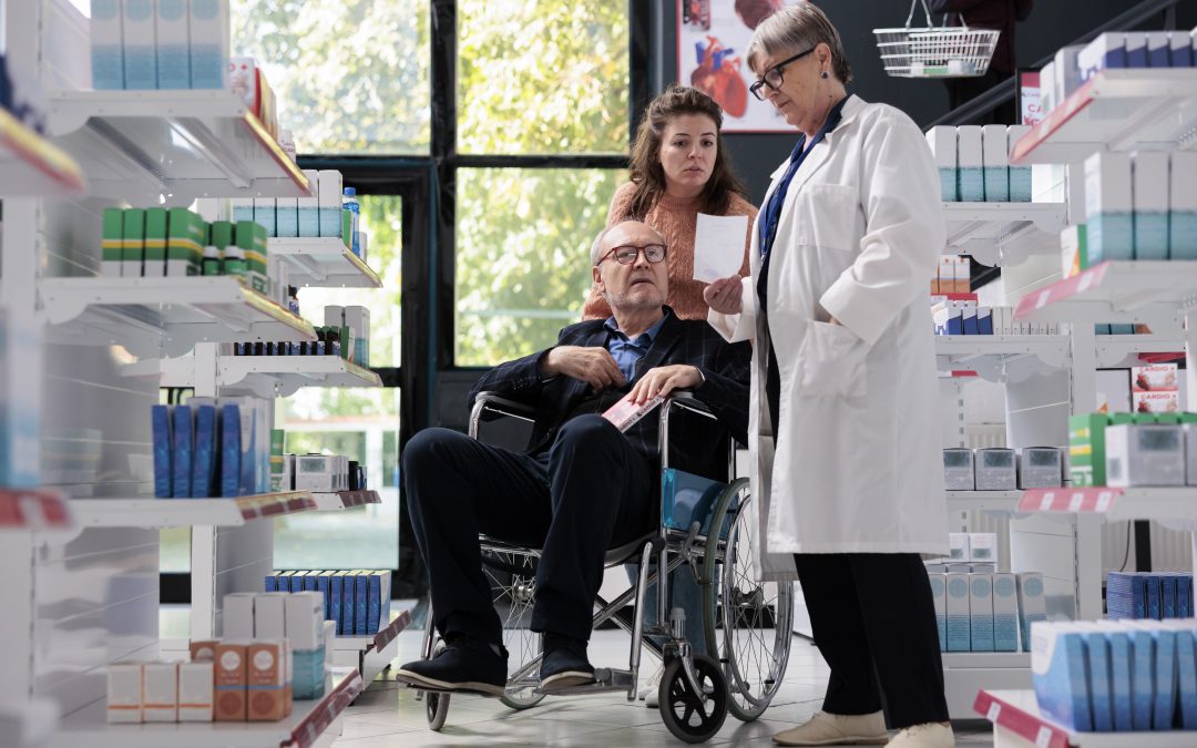 Pharmacien aidant un client en fauteuil roulant dans une pharmacie